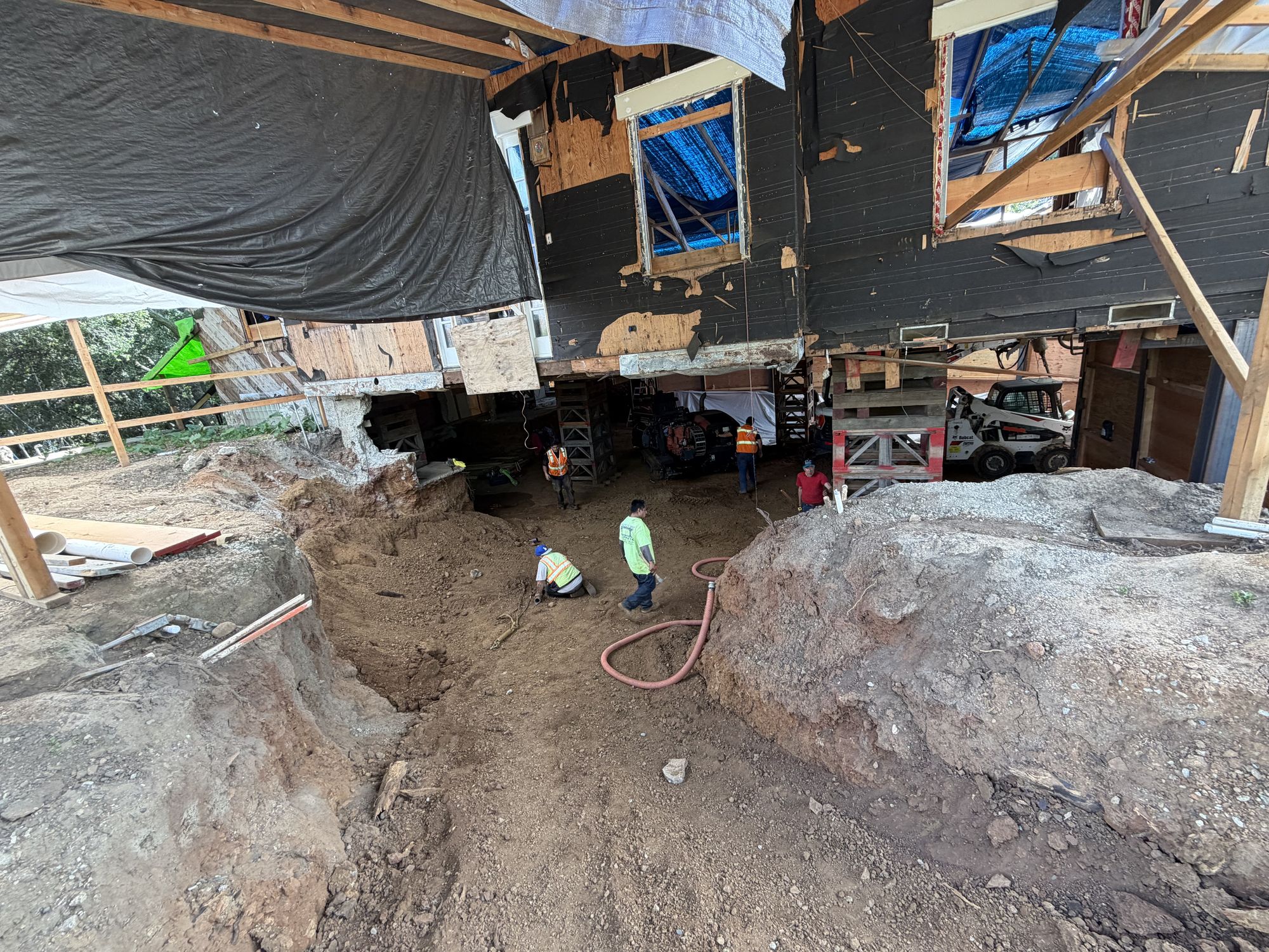 Wide view of the basement excavation with crew and mud hose