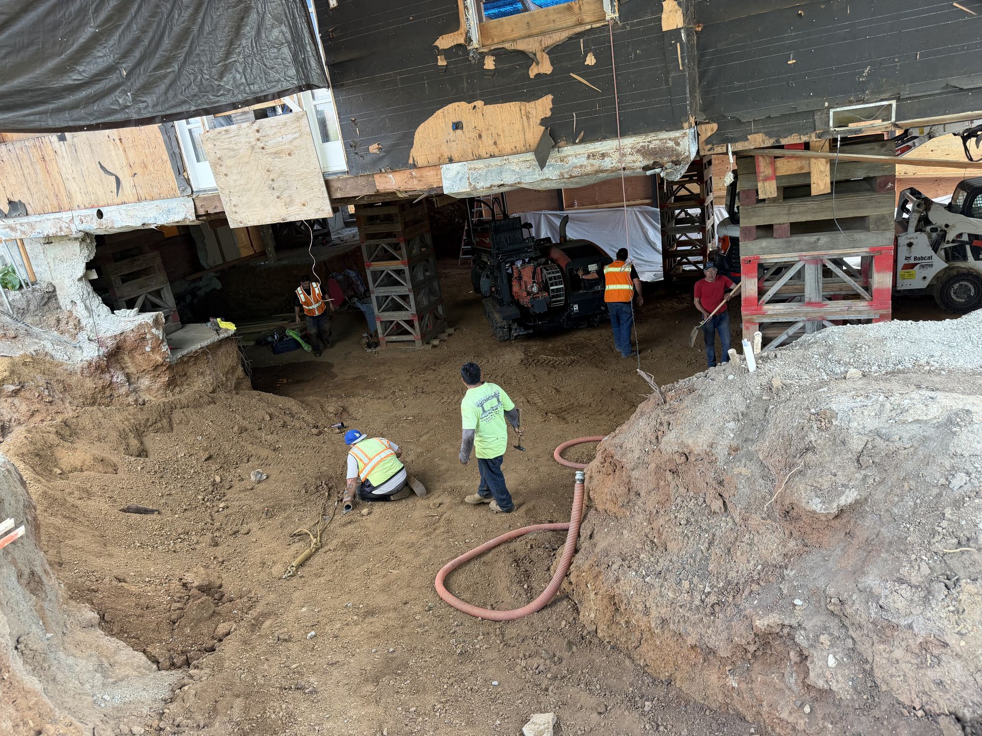 Apex crew working in the excavated basement under a house raised on cribbing
