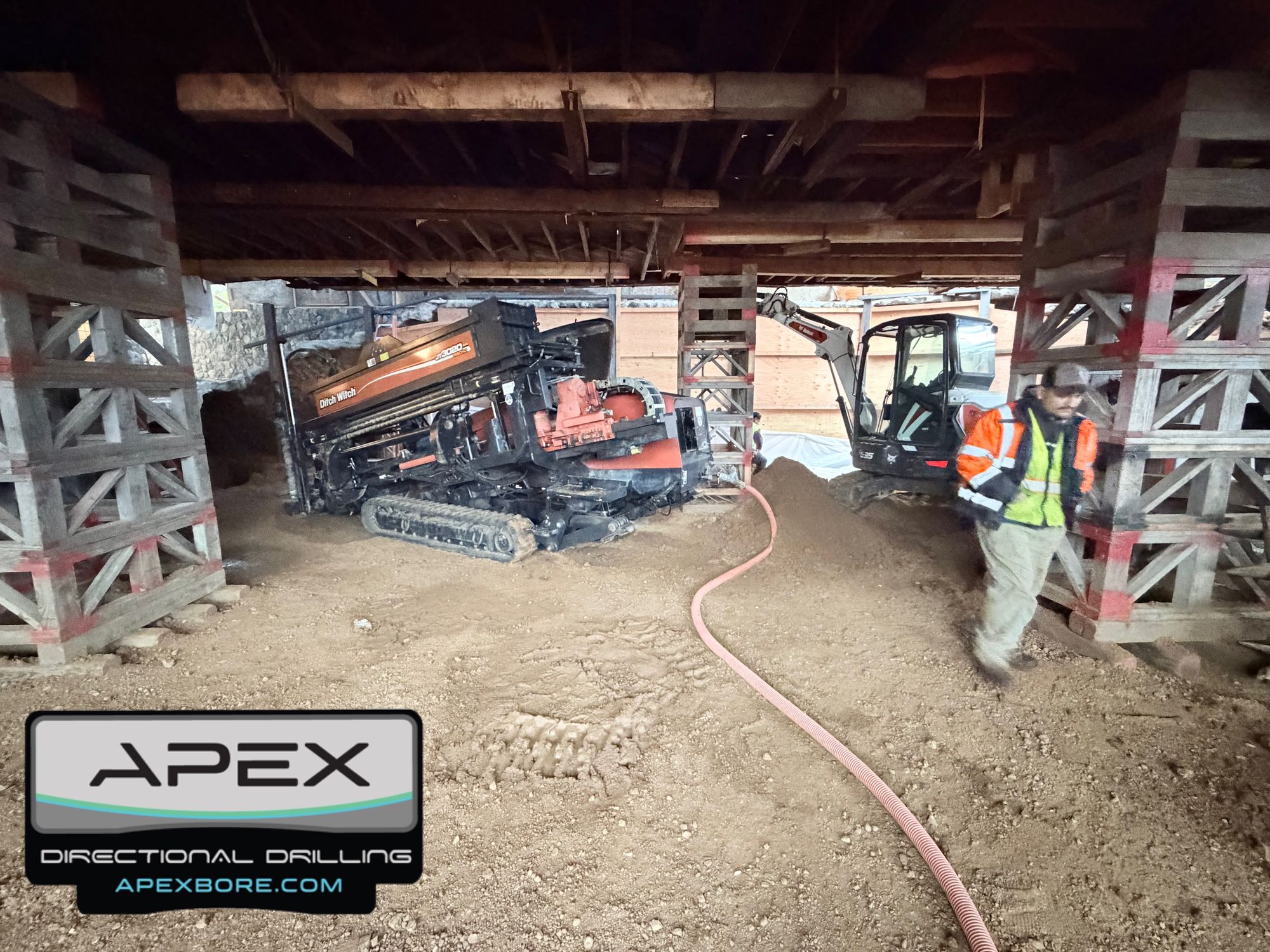 Drill rig between cribbing towers with the hydrovac mud hose run in