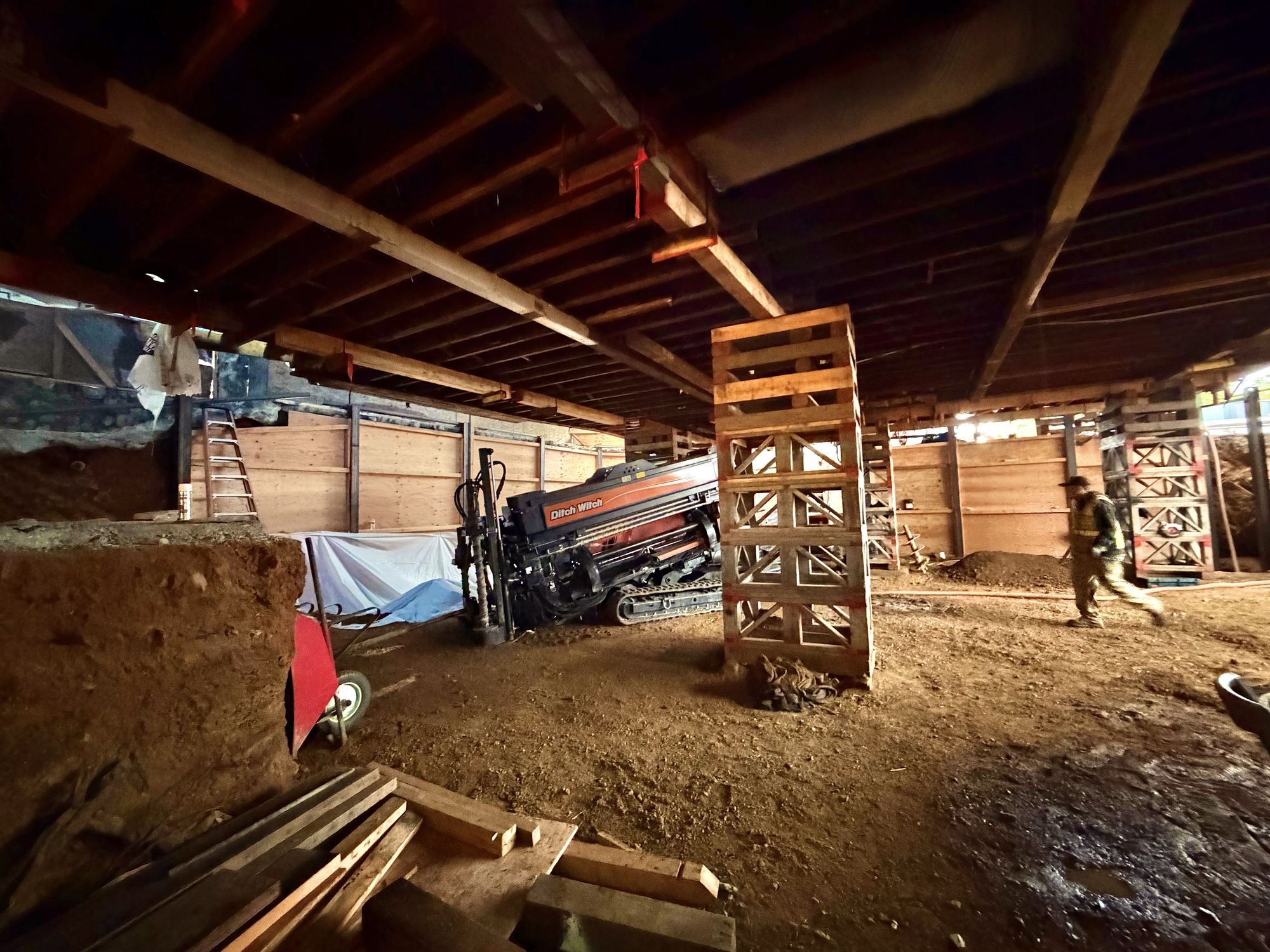 Directional drill rig set up under the floor framing of the house