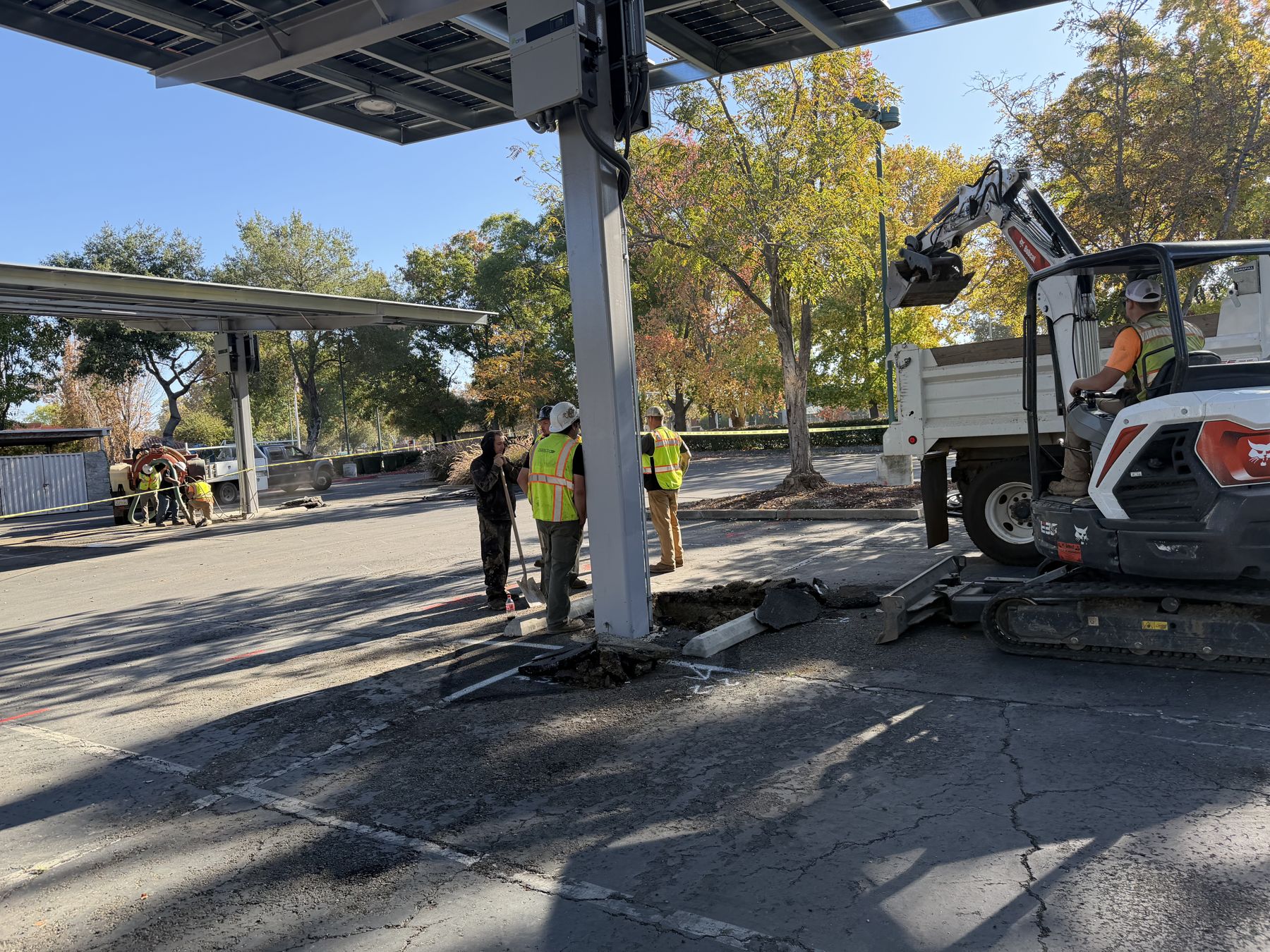 Crew and mini excavator working at a solar canopy column