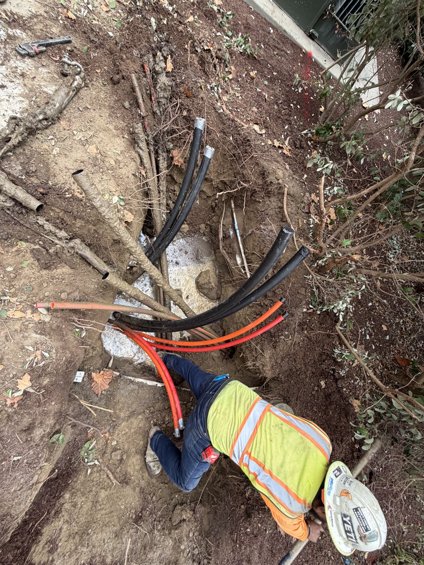 Crew member tying in several conduits in an excavation