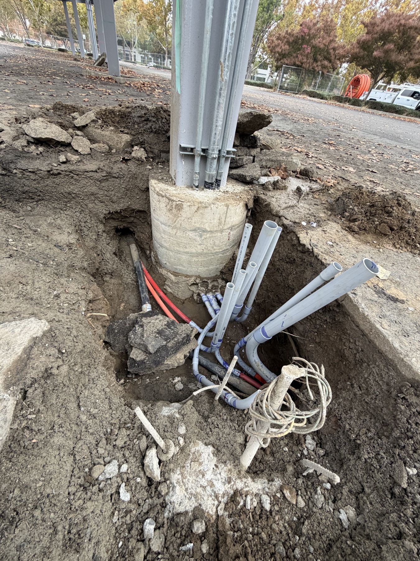 Gray PVC conduit sweeps stubbed up at the concrete footing of a solar carport column