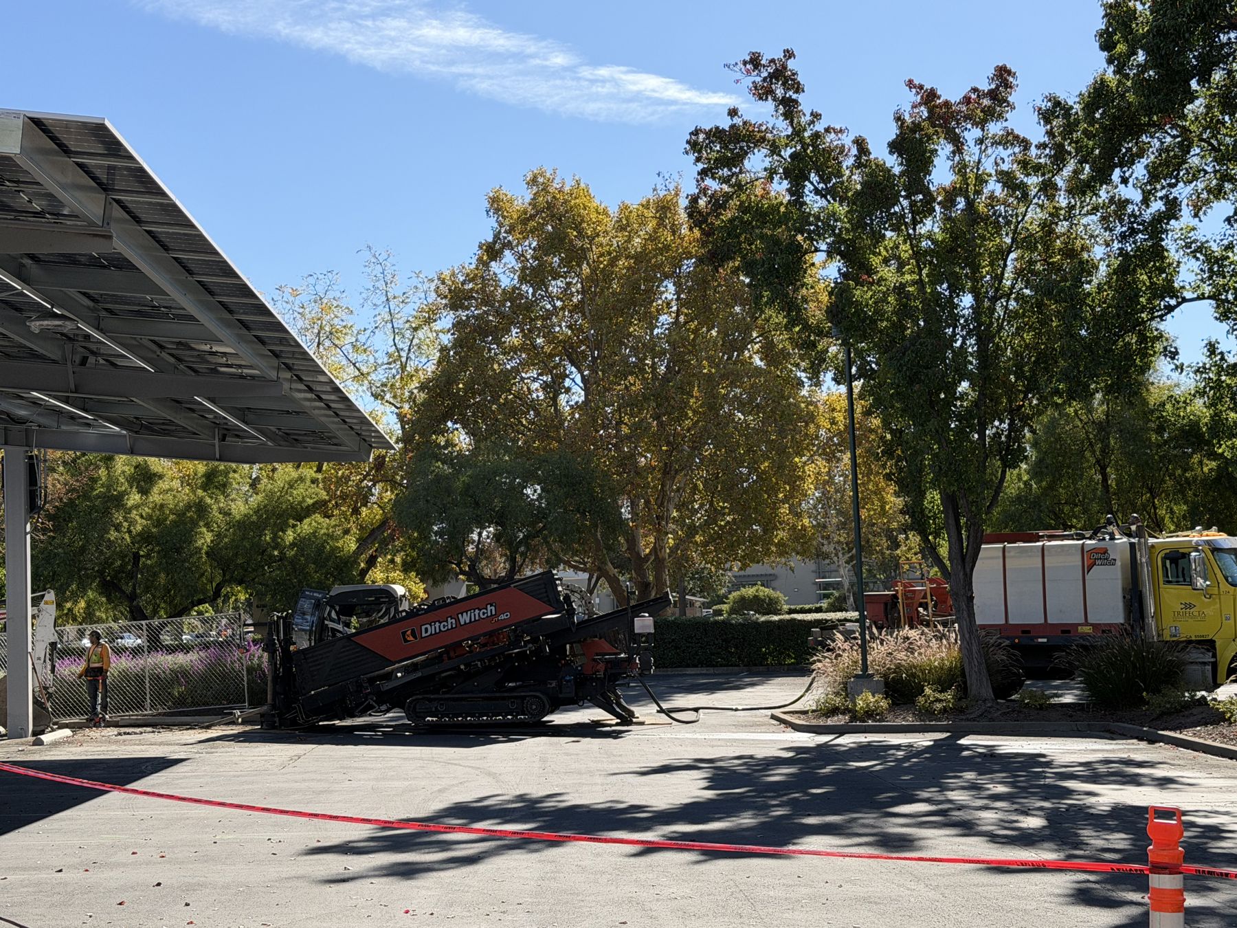 Drill rig beside a solar carport with the parking lot open around it