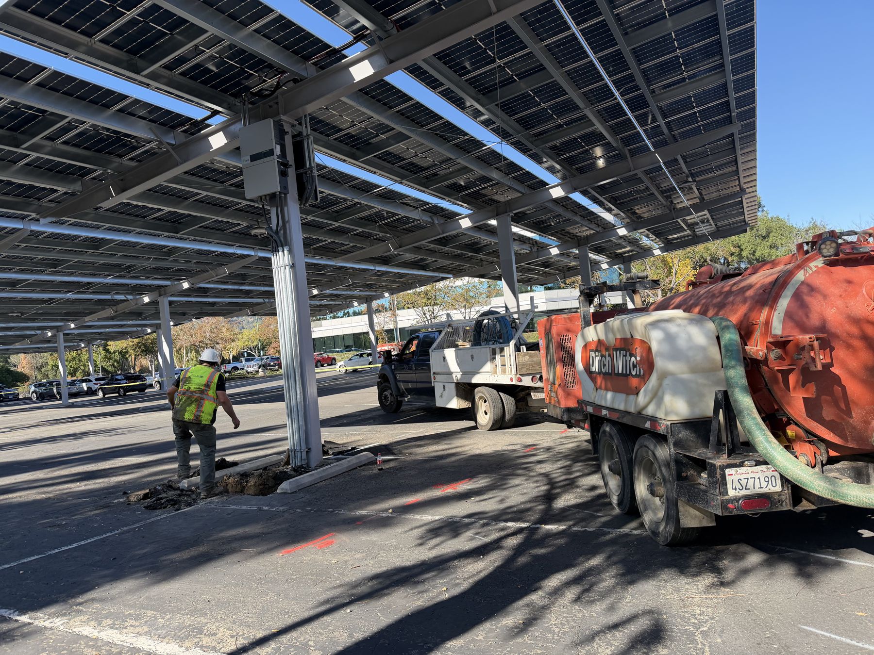 Crew potholing at a carport column while a hydrovac truck works nearby