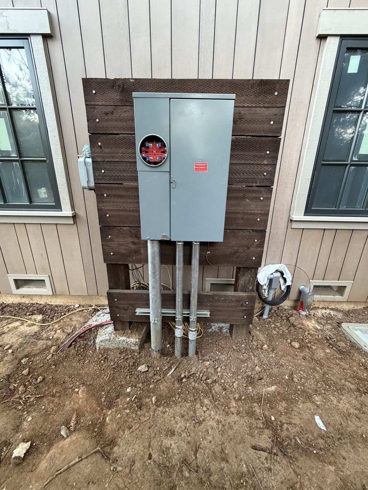 New conduit stubbed up below an electric meter on a house