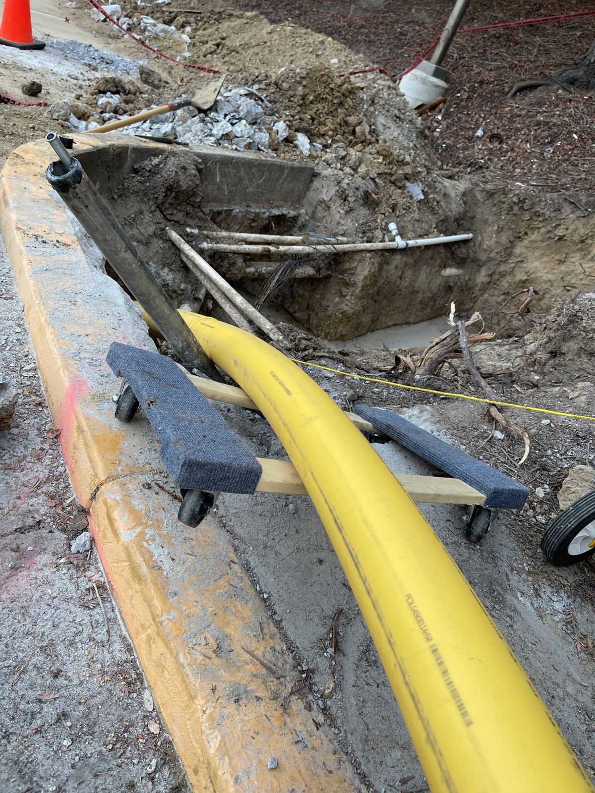 Yellow gas service pipe coming out of a small exit pit at the curb